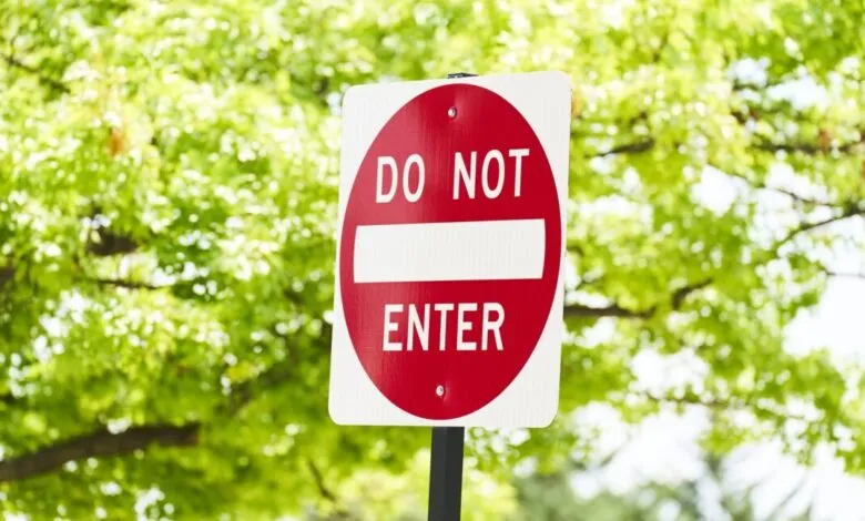 Red and white 'Do Not Enter' sign against green foliage.