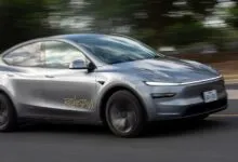 Gray electric vehicle driving on a road with blurred background.