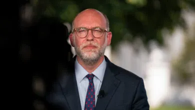 Russell Vought in suit and tie, wearing glasses, looking at camera.