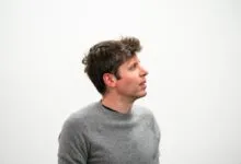 Man in gray sweater looking up against a white background.