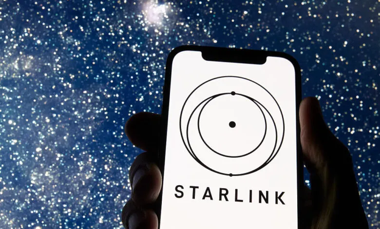Starlink logo on smartphone screen against a starry night sky background.