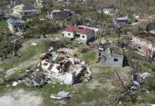 Aerial view of homes damaged by a hurricane, debris scattered around.