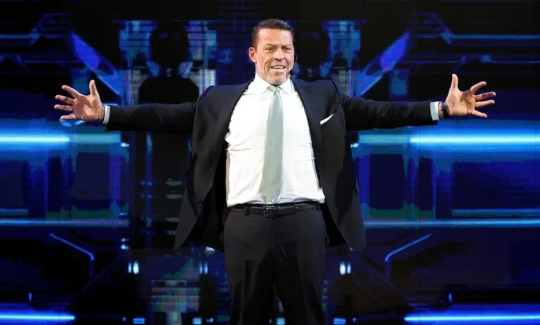 Tony Robbins on stage with arms outstretched, smiling.