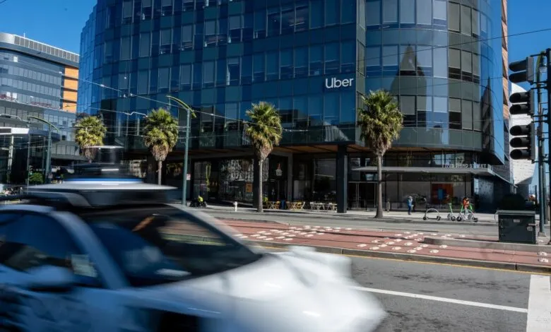 Uber building with self-driving car in motion on city street.