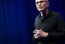 Satya Nadella, Microsoft CEO, speaks on stage with hands clasped.