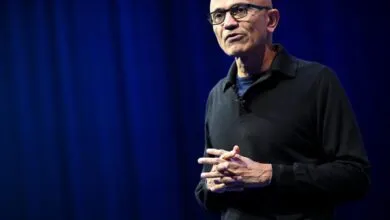 Satya Nadella, Microsoft CEO, speaks on stage with hands clasped.