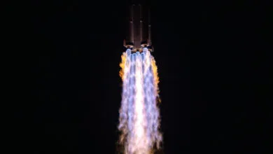 Rocket ascending with bright flames against a dark sky.