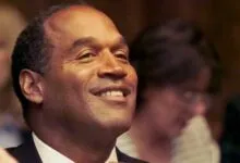 O.J. Simpson smiles in court, adjusting his tie during jury selection.