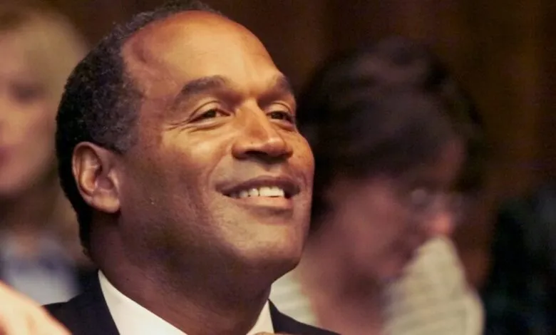 O.J. Simpson smiles in court, adjusting his tie during jury selection.