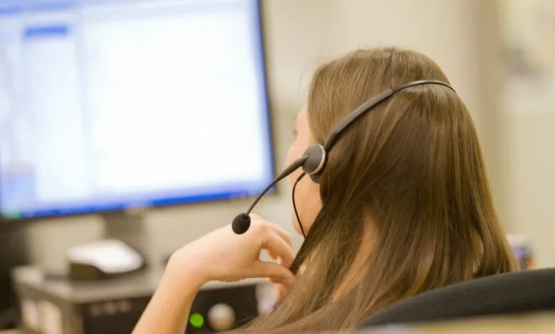 Woman with headset working at computer, back view