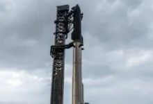 SpaceX Starship rocket and launch tower against a cloudy sky.