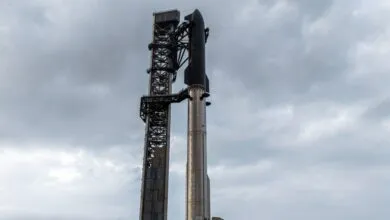SpaceX Starship rocket and launch tower against a cloudy sky.