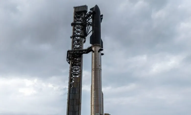 SpaceX Starship rocket and launch tower against a cloudy sky.