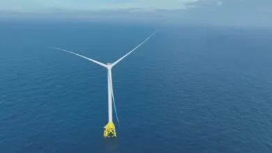 Offshore wind turbine stands in the ocean with blue water.