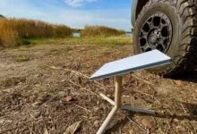Starlink dish setup outdoors near a vehicle and lake, providing remote internet access.