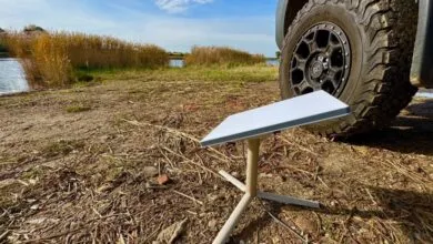 Starlink dish setup outdoors near a vehicle and lake, providing remote internet access.