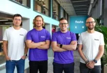 Four men wearing Fresha branded shirts stand with arms crossed.