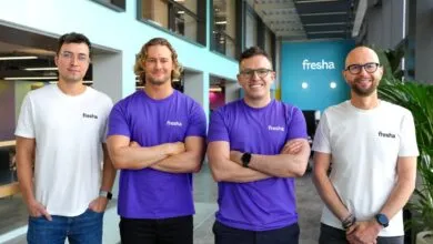 Four men wearing Fresha branded shirts stand with arms crossed.