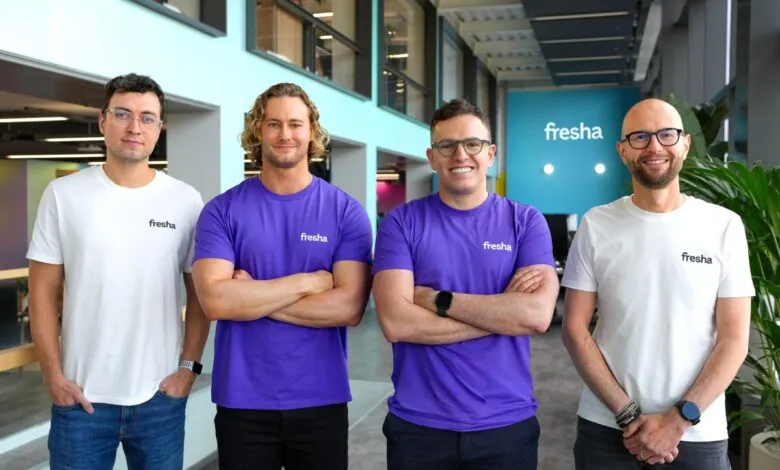 Four men wearing Fresha branded shirts stand with arms crossed.