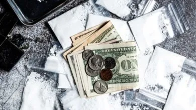 Money, bags of white powder, and a lighter on a textured surface.