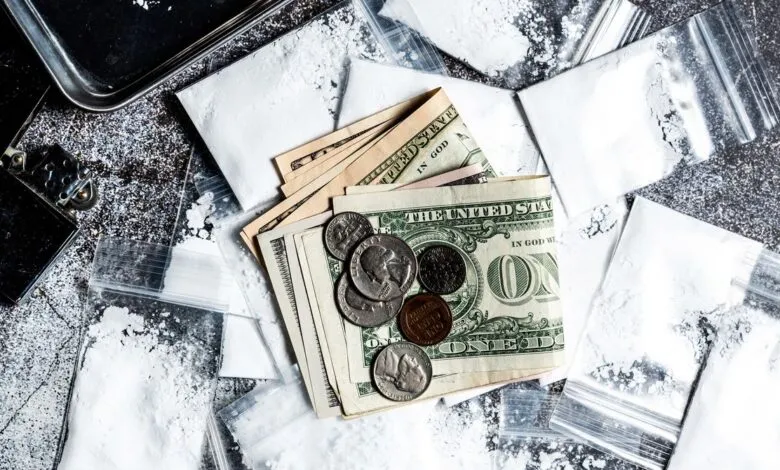 Money, bags of white powder, and a lighter on a textured surface.
