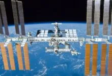 The International Space Station orbits above Earth, solar panels extended.