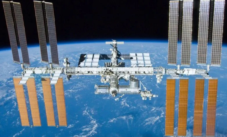 The International Space Station orbits above Earth, solar panels extended.