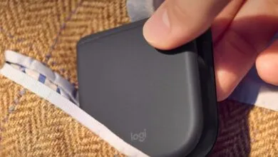 Logitech folding mouse being placed into a tweed jacket pocket.