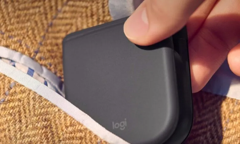 Logitech folding mouse being placed into a tweed jacket pocket.