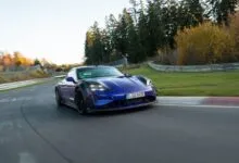 Blue Porsche Taycan Turbo GT driving on a racetrack with trees in the background.