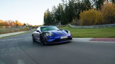 Blue Porsche Taycan Turbo GT driving on a racetrack with trees in the background.