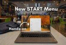 Lenovo laptop displaying the new Windows 11 Start Menu in a cafe setting.