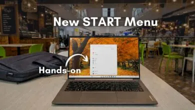 Lenovo laptop displaying the new Windows 11 Start Menu in a cafe setting.