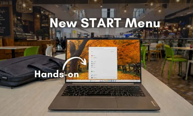 Lenovo laptop displaying the new Windows 11 Start Menu in a cafe setting.