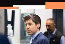 Sam Altman in a blue suit looks to the side with a serious expression.