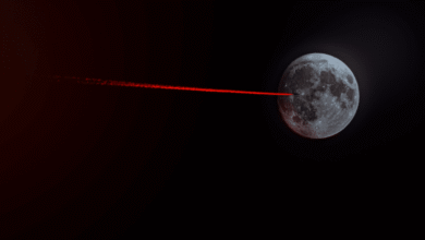 The Moon with a red laser beam pointing towards it in a dark space background.