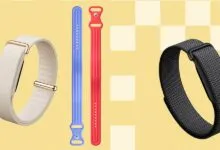 Three Fitbit fitness trackers with different colored bands on a yellow background.