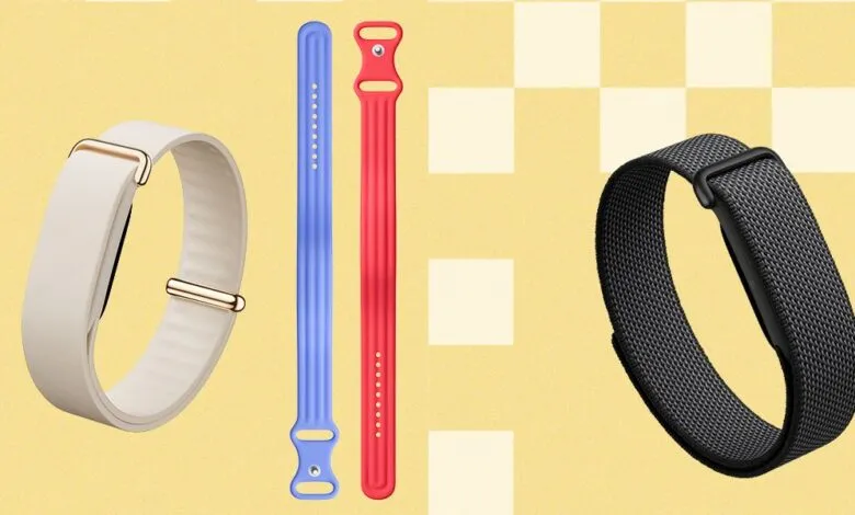Three Fitbit fitness trackers with different colored bands on a yellow background.