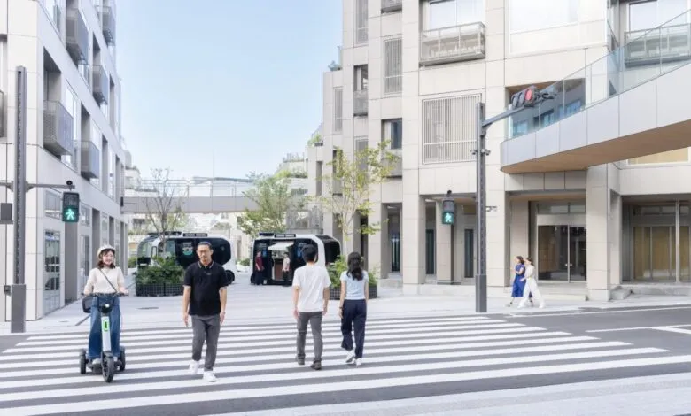 People cross a street with autonomous vehicles in a modern urban setting.
