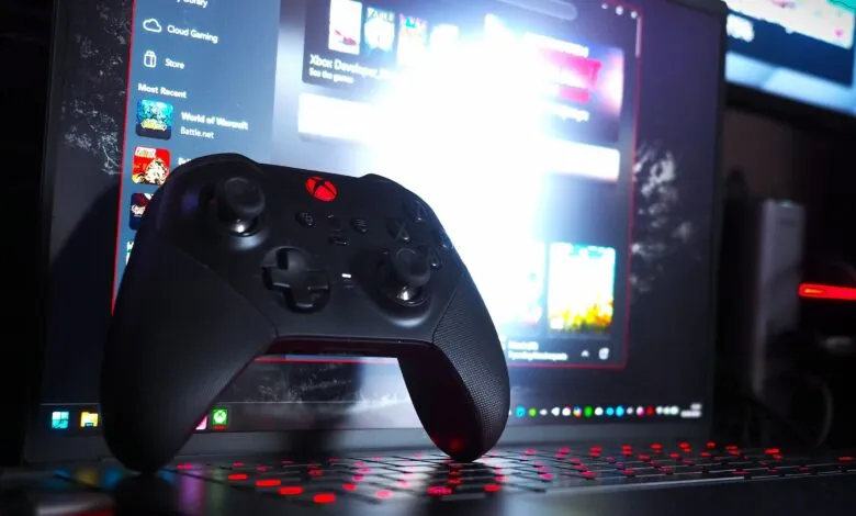 Xbox controller rests on a laptop with a gaming interface displayed.