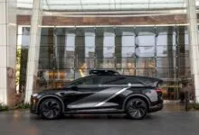 Black Nuro autonomous vehicle parked in front of modern building.