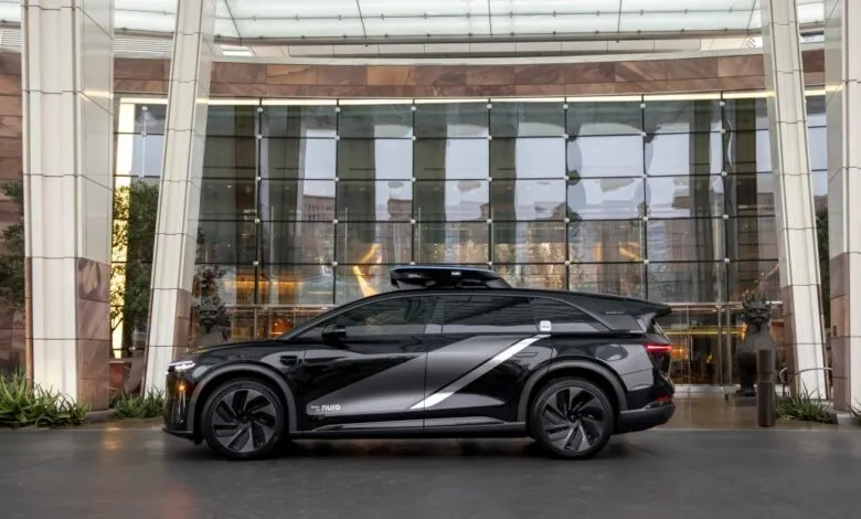 Black Nuro autonomous vehicle parked in front of modern building.