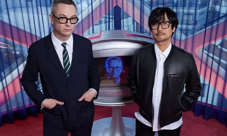 Sean Evans and Hideo Kojima pose in front of a retro-futuristic screen.