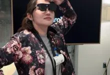 Woman wearing smart glasses, floral jacket, and Google Guest badge.