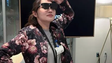 Woman wearing smart glasses, floral jacket, and Google Guest badge.