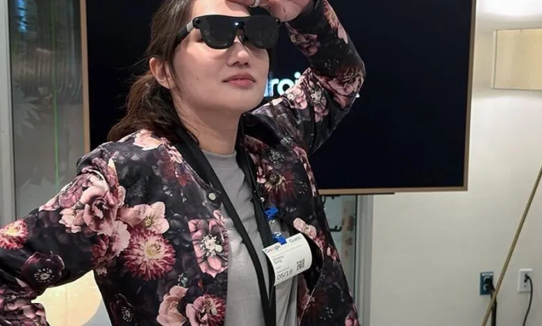 Woman wearing smart glasses, floral jacket, and Google Guest badge.