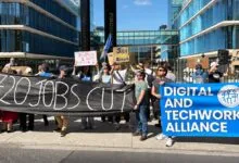 Protesters outside Meta building holding signs about job cuts and fair treatment.