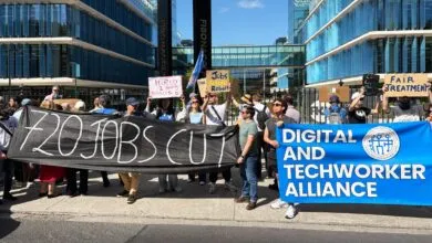 Protesters outside Meta building holding signs about job cuts and fair treatment.