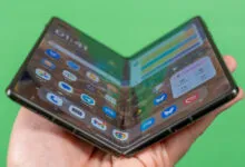 Foldable smartphone held open in hand, displaying app icons.