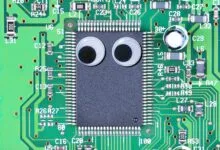 Circuit board with googly eyes on chip, creating a funny face.